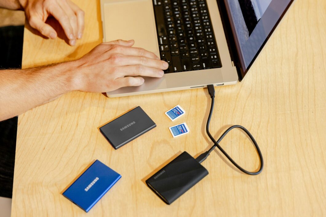 imagem de um notebook ao lado de HDs externos e cartões de memória