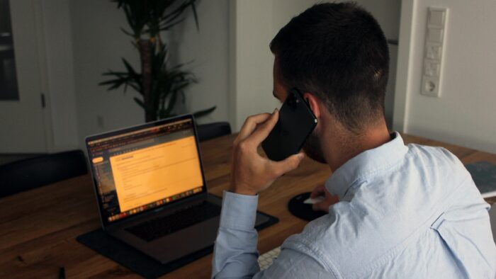 Pessoa falando ao telefone e mexendo no computador