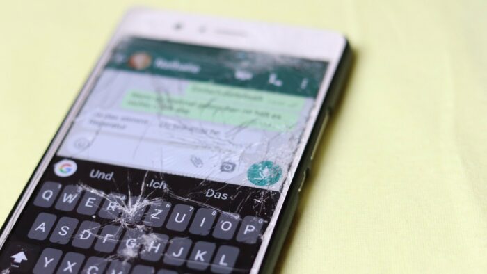Imagem de um celular quebrado em cima de uma mesa com o WhatsApp aberto