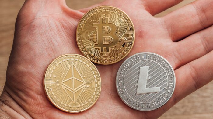 Moedas de bitcoin, ether e litecoin na mão