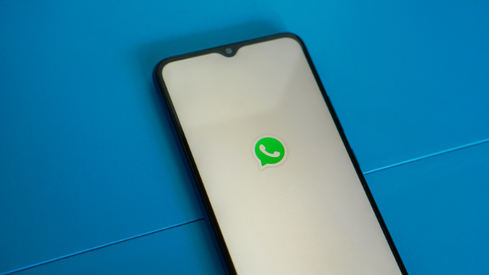 imagem de celular com logo do whatsapp em um fundo azul representando o uso do recurso áudio