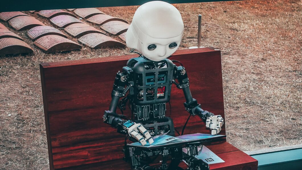 Robô humanoide sentado e segurando tela