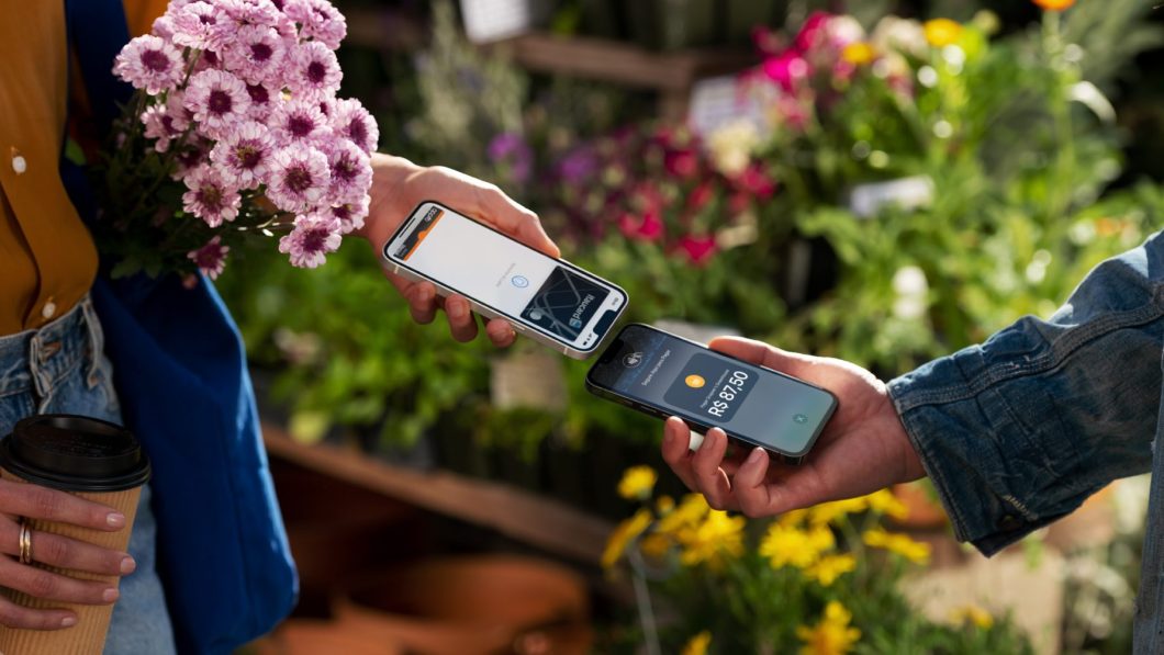 Pessoa aproxima smartphone de outro smartphone numa floricultura