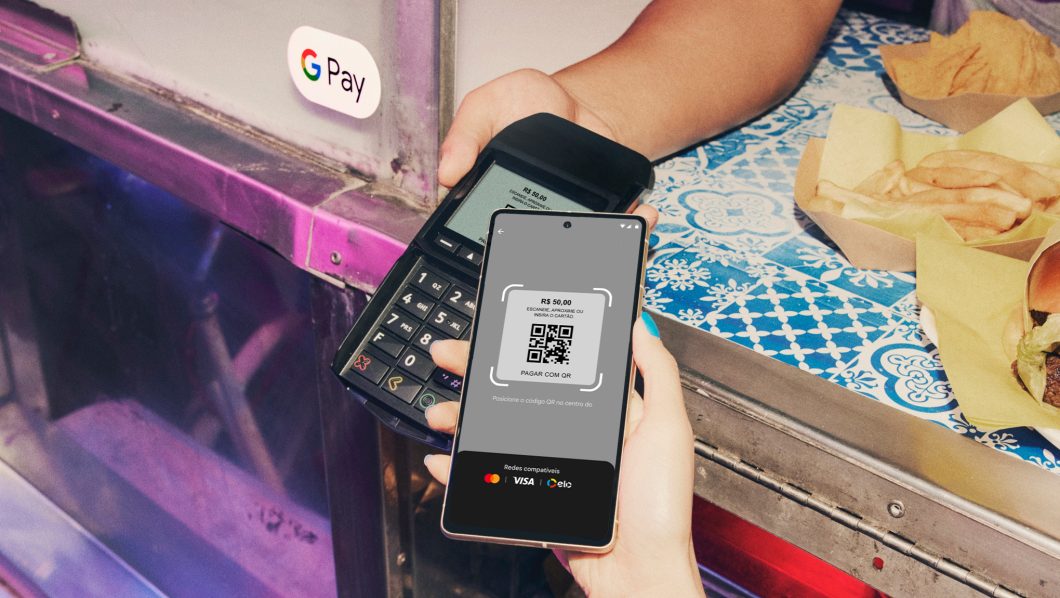 Pessoa usando um celular para ler o QR Code de uma maquininha de cartão em uma hamburgueria
