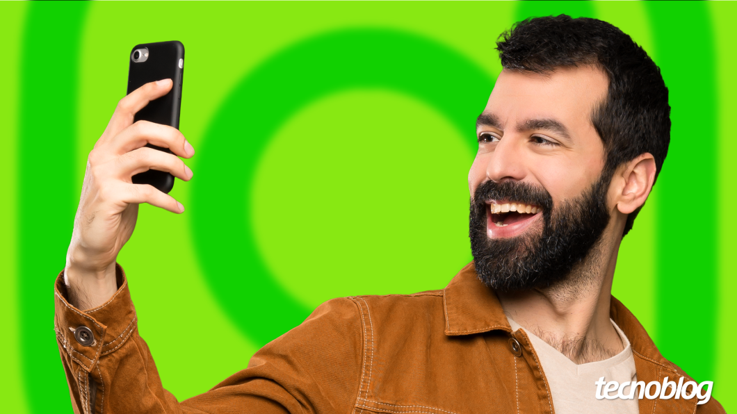 Homem de barba parado na frente do celular com um verde com o logotipo do Instagram