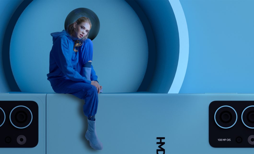 Imagem publicitária mostra mulher sentada sobre celular HMD gigante