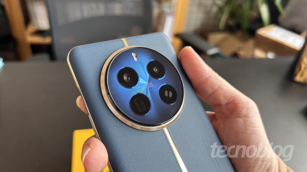 Mão segurando o smartphone da Realme, Realme 12 Pro Plus, na cor azul, em um fundo desfocado