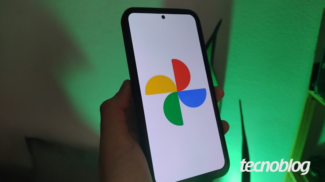 Imagem de uma mão segurando um celular Samsung exibindo o logo do Google Fotos