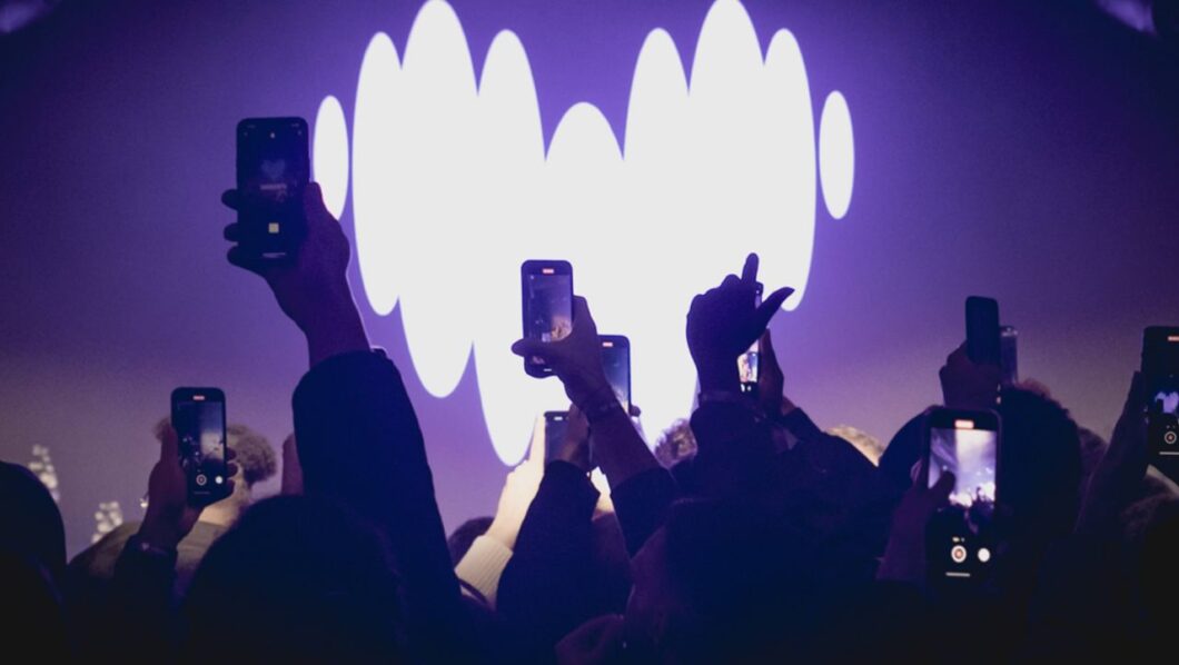 Palco com o logotipo da Deezer no fundo e várias mãos filmando o palco com o celular