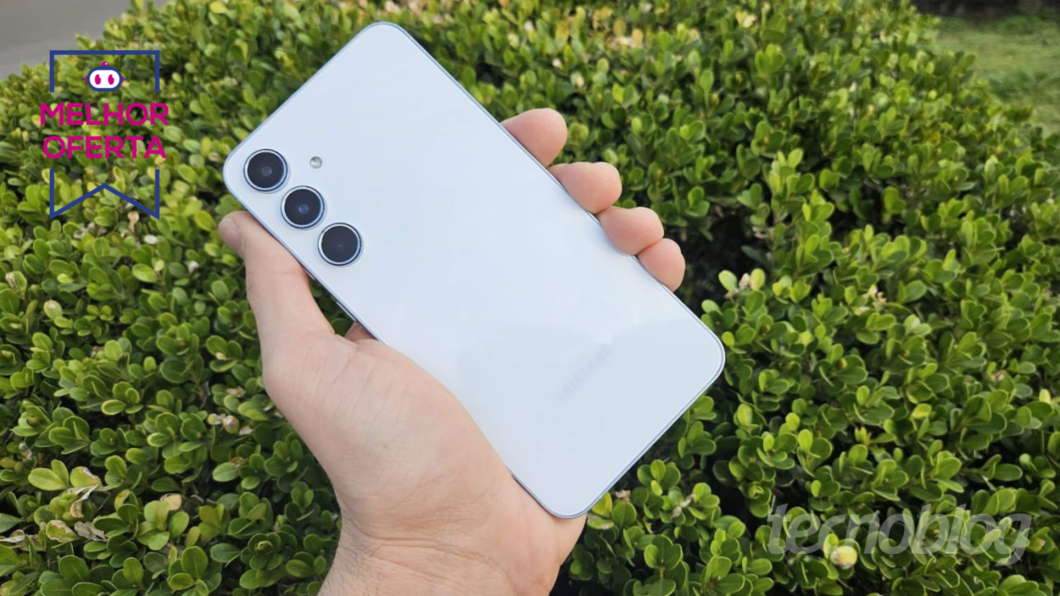 Mão segurando o Galaxy A55 com arbusto atrás