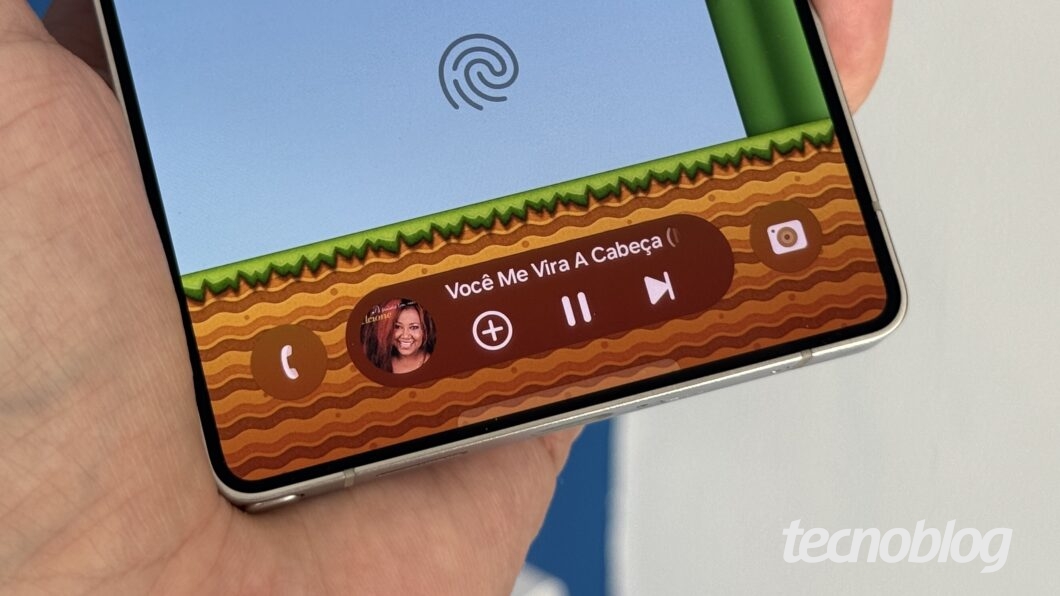 Mão segurando celular, com detalhe para Now Bar no canto inferior da tela