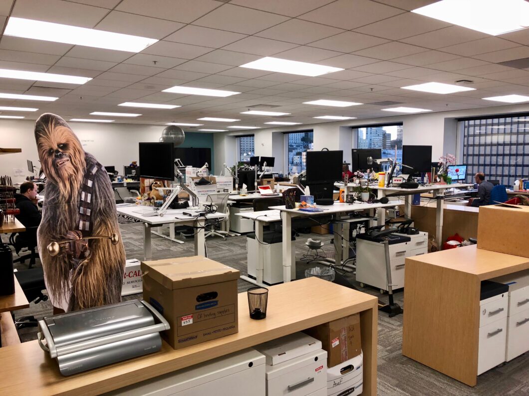 Escritório com mesas e cartaz do Chewbacca, personagem de Star Wars.