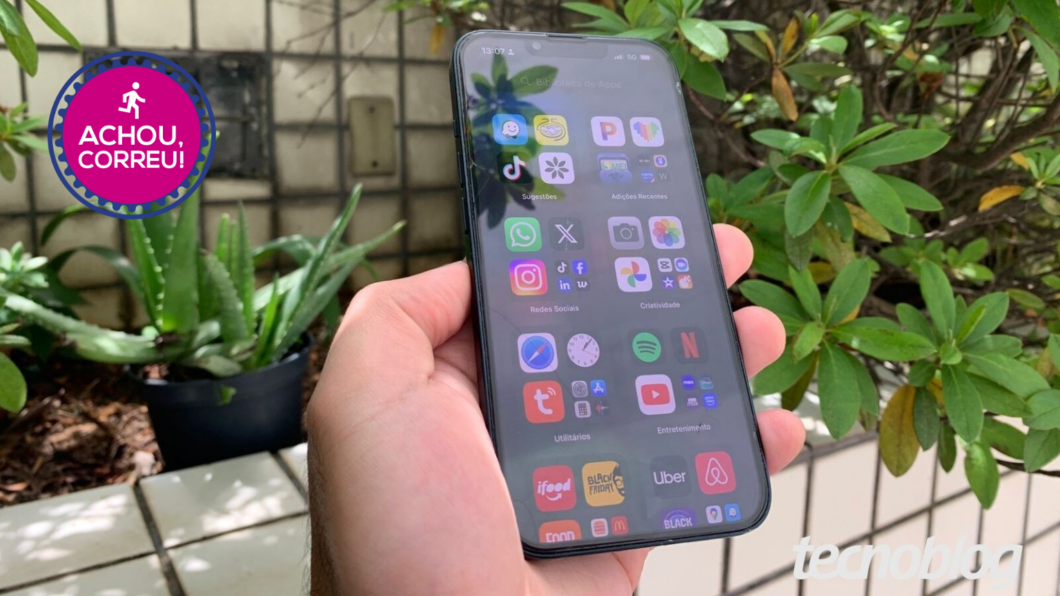 Mão segurando o iPhone 13 com jardim ao fundo