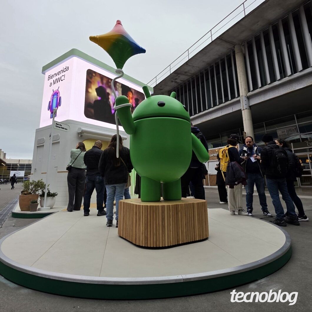 Foto de um boneco do Android no início de um estande, com pessoas no entorno