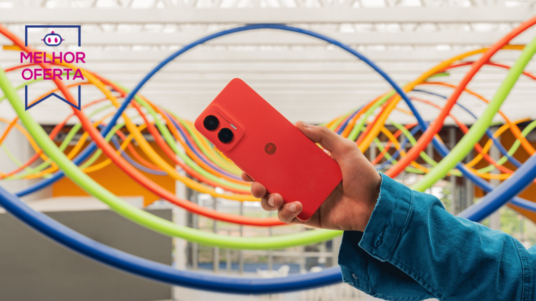 Mão segurando um Moto G35 coral com um fundo colorido atrás