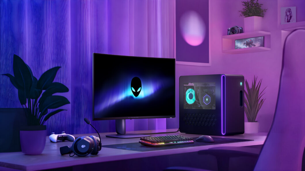 Um setup de computador gamer com iluminação roxa e azul. Um monitor Alienware exibe um logotipo de alienígena na tela. Ao lado, um gabinete de computador com painel lateral transparente mostra componentes internos iluminados. Na mesa, há um teclado RGB, um mouse, um headset com microfone e um controle de videogame. Ao fundo, há uma parede com prateleiras contendo uma câmera, um vaso de planta e uma imagem decorativa. Cortinas translúcidas cobrem uma janela, e uma cadeira gamer está posicionada em frente à mesa.