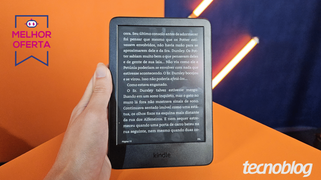 Mão segurando o Kindle com fundo laranja atrás