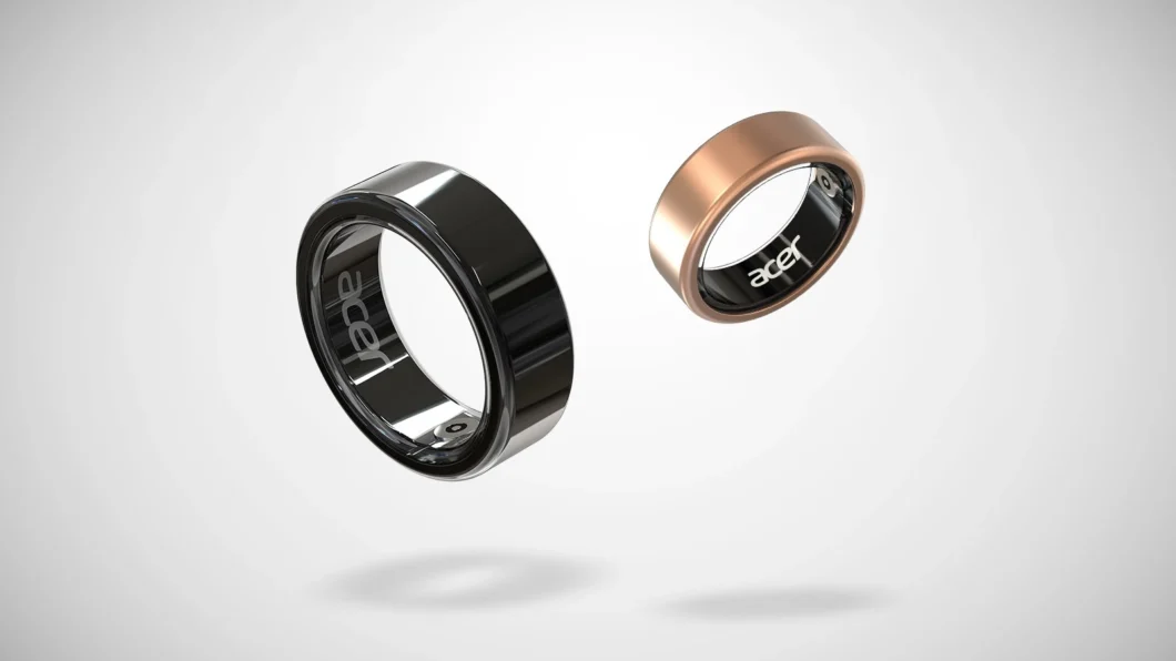 Anéis inteligentes da Acer em close, um preto brilhante e outro dourado fosco, flutuando sobre um fundo cinza claro, com sombras projetadas abaixo. A palavra "acer" está visível na parte interna dos anéis.