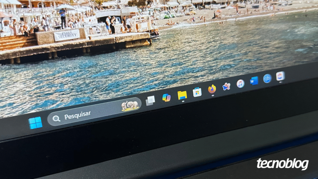 Barra de tarefas do Windows com ícones visíveis sobre fundo de praia.