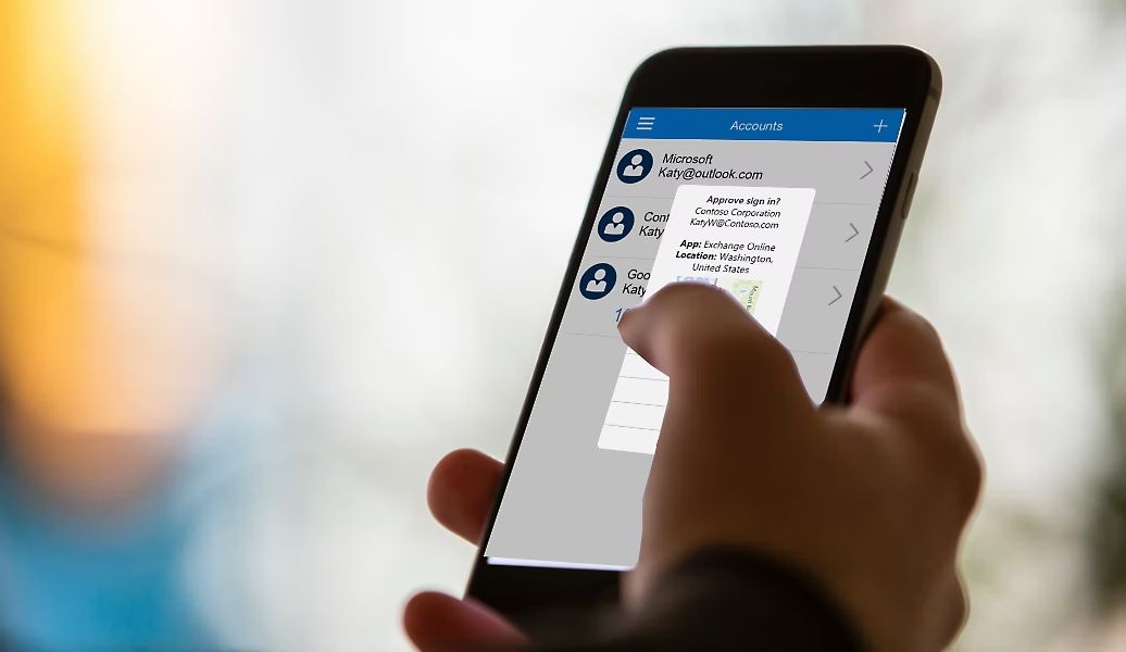 Mão segurando um celular com o Microsoft Authenticator aberto