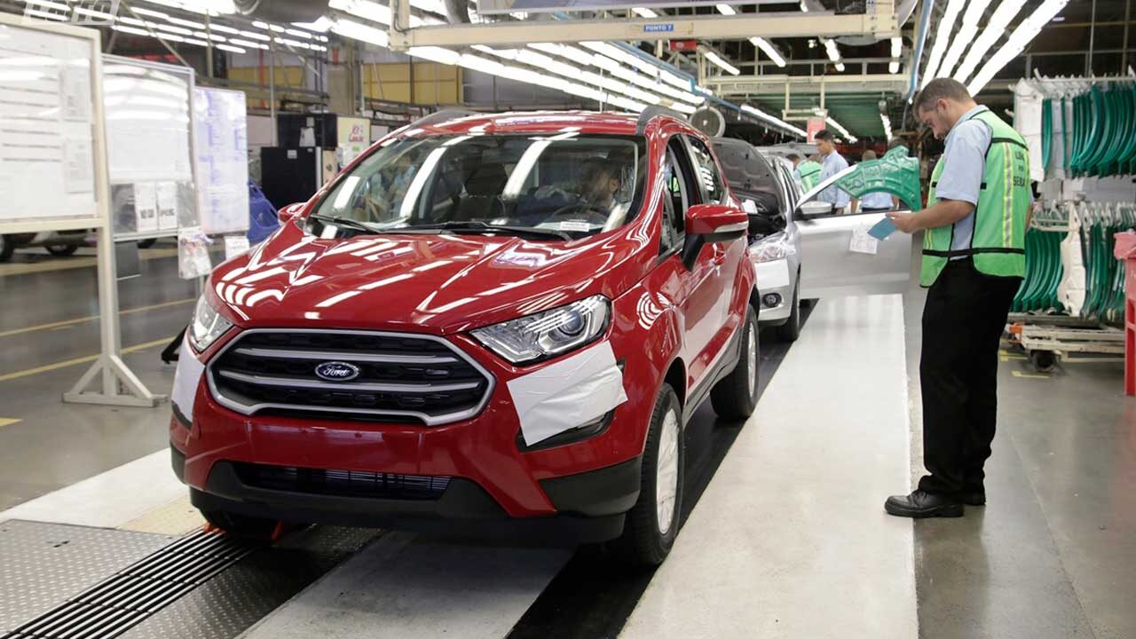 Funcionários inspecionando veículos na linha de montagem da Ford