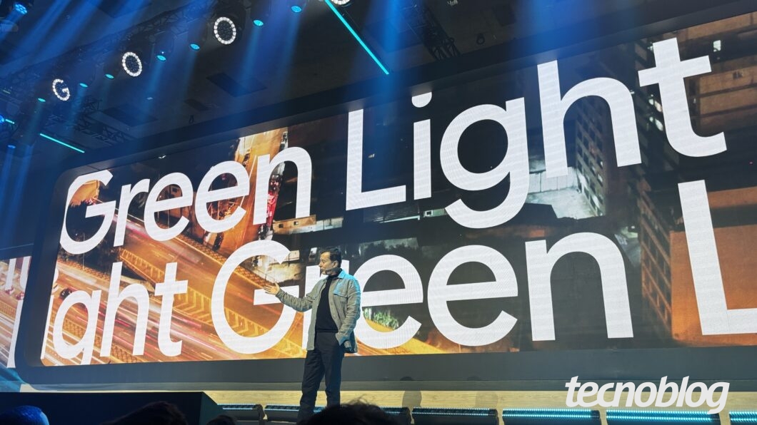 Executivo Fábio Coelho em palco de evento. Atrás, um telão mostra uma imagem de uma cidade e o texto "Green Light"