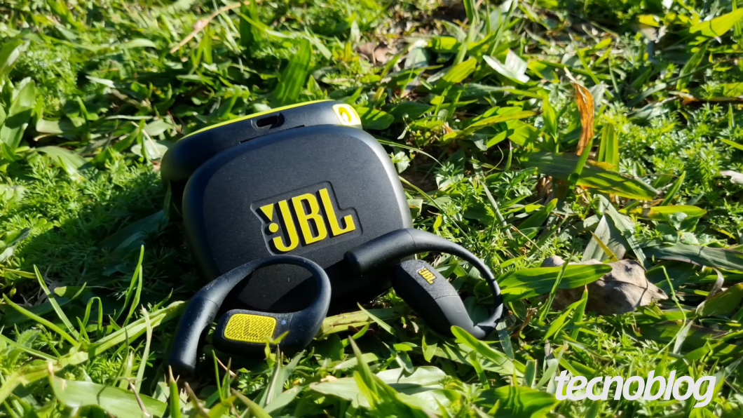 JBL Endurance Zone, fone open ear para treinos, em grama com cabo e estojo da case ao lado