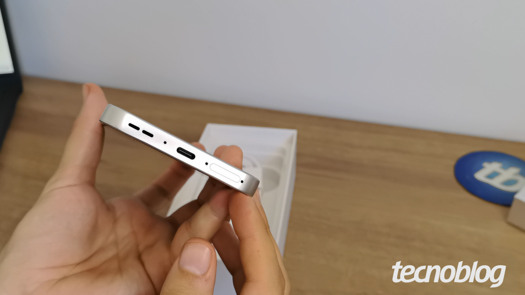 Detalhe lateral do Oppo Reno 16 F branco, mostrando botões e entrada inferior de som