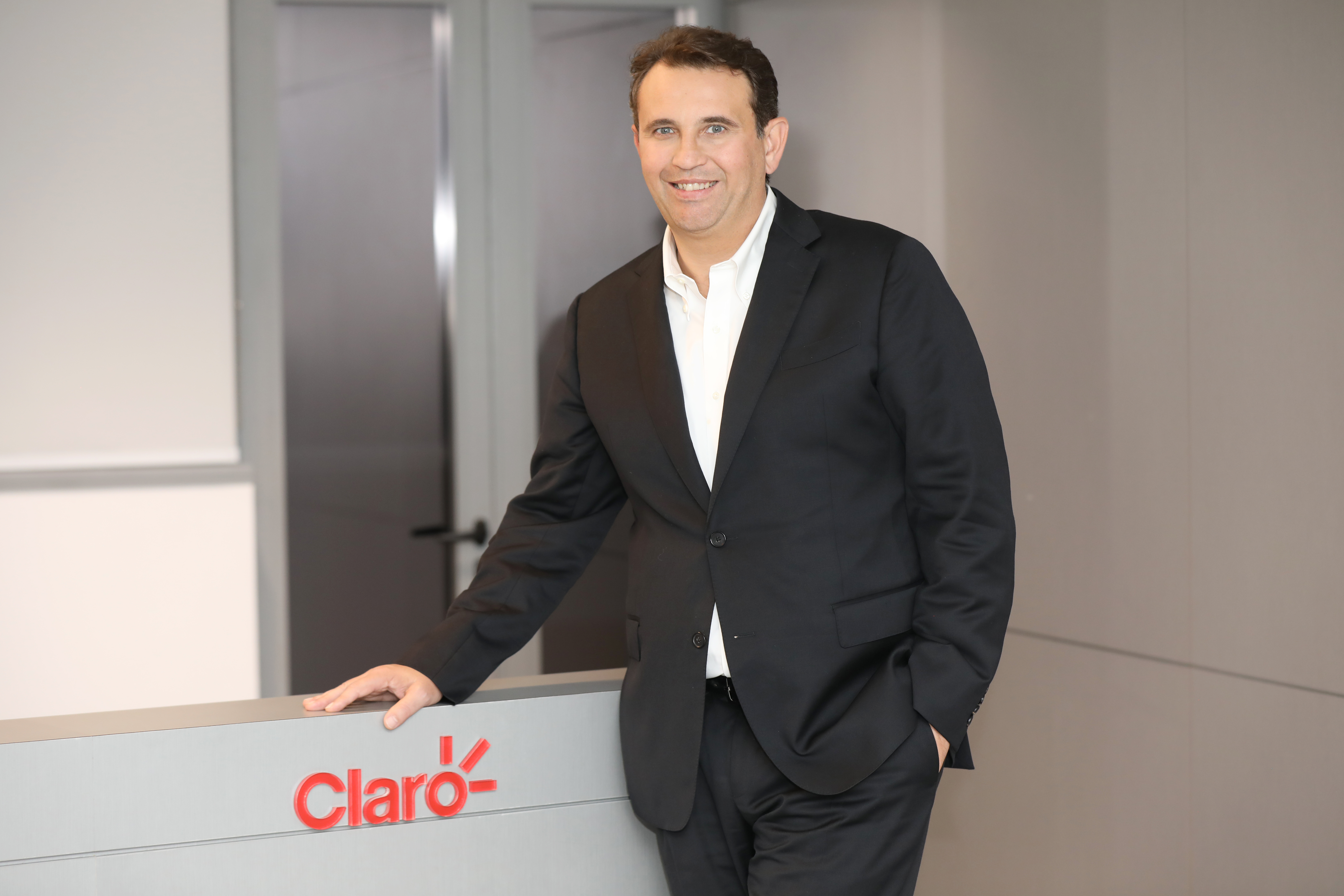 Márcio Carvalho, CMO da Claro, apoiado em bancada com o logo da empresa.