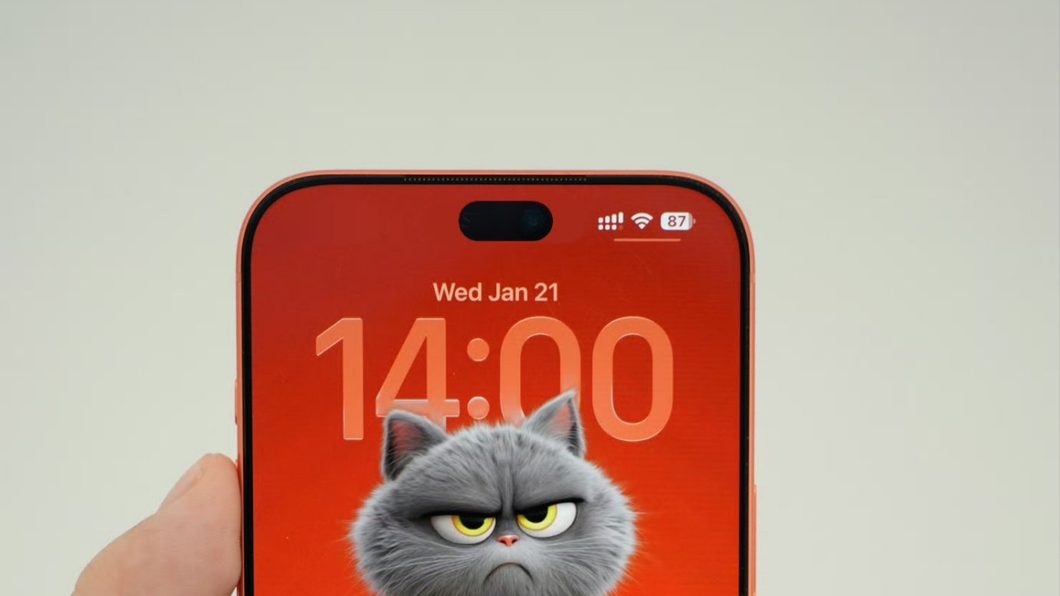 mockup de um iPhone 18 Pro visto de frente. A imagem mostra a tela acesa, apresentando um wallpaper com fundo laranja e um gato cinza, dando destaque à Ilha Dinâmica menor na parte superior