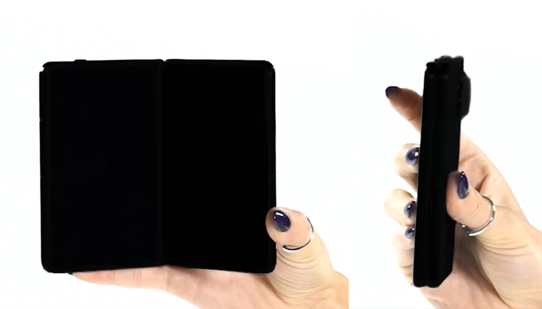 Imagem mostra um celular dobrável inteiramente preto sendo segurado em uma mão. O fundo da imagem é branco