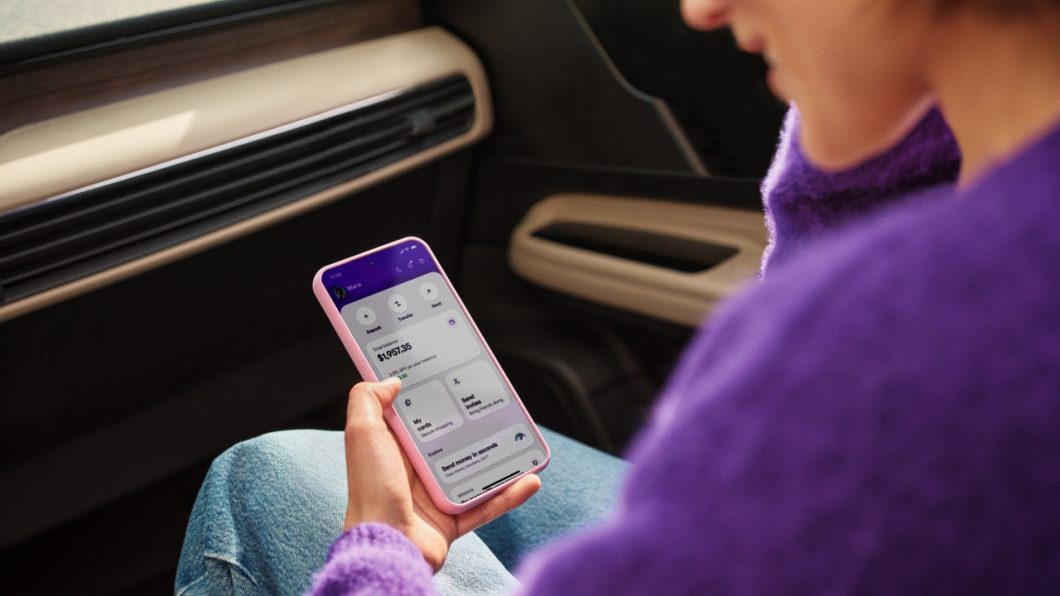 Mulher segurando celular com app do Nubank dos EUA